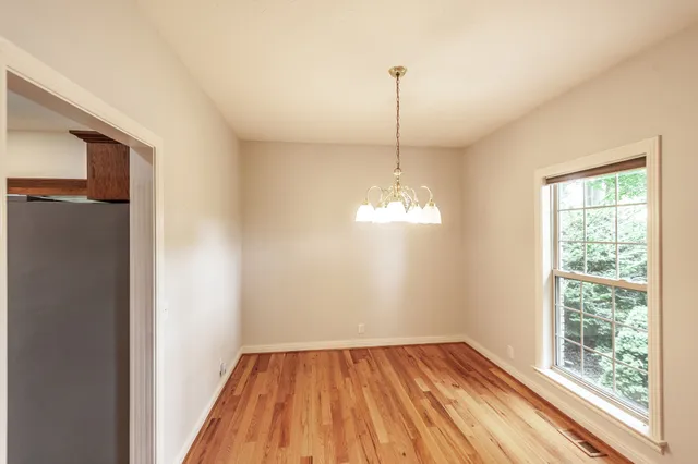 a view of a room with wooden floor chandelier and a window