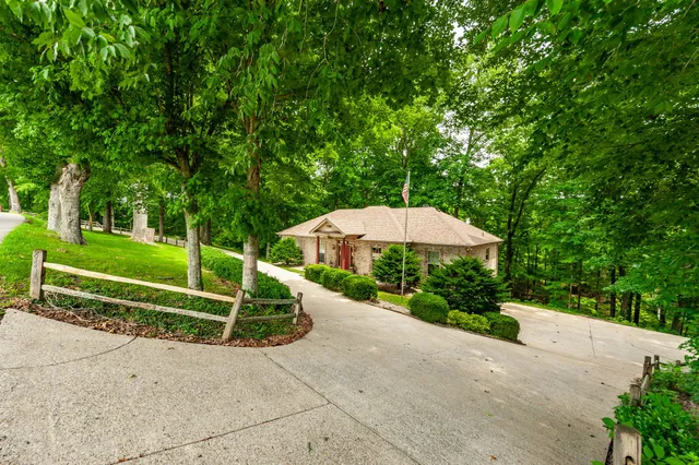 a view of a street with a small yard and large trees