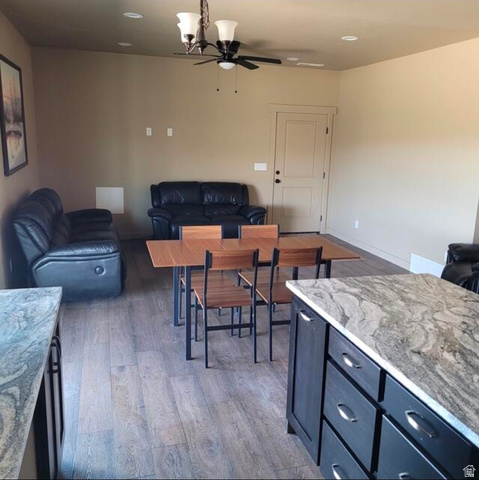 9381 South Sevier Riv Ranch Levan, UT 84639 - Photo 11 of 58 Open-concept living area featuring wood-finish flooring throughout, a dining table with seating for four, dark leather reclining seating, and a chef's kitchen with stone-finish countertops and dark cabinetry
