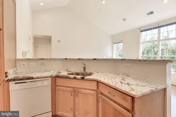 a large kitchen with granite countertop a stove top oven a sink a counter space wooden floor and cabinets