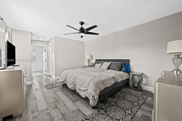 a bedroom with a bed a mirror on dresser and a flat screen tv