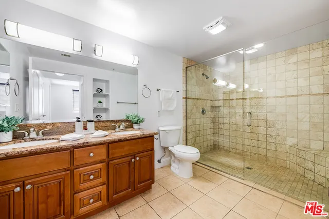 a spacious bathroom with a granite countertop sink a toilet a mirror and shower