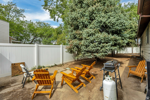 6709 Acoma Road, Unit 239 Midvale, UT 84047 - Photo 37 of 38 6709 - Enclosed outdoor area featuring a white privacy fence and mature evergreen trees