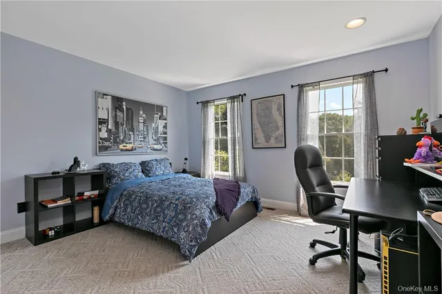a bedroom with a bed a desk chair and windows