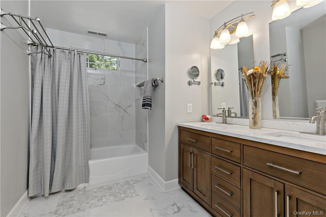 4 Sonoma Road Cortlandt Manor, NY 10567 - Photo 20 of 31 a bathroom with a double vanity sink a mirror a bathtub and shower
