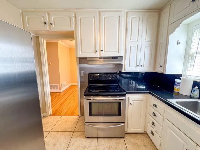 a kitchen with granite countertop white cabinets and white appliances