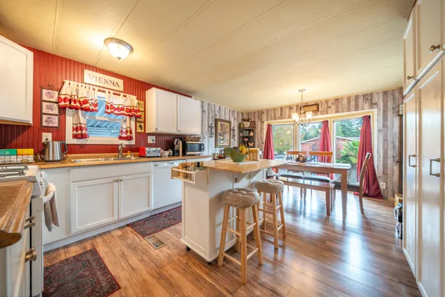 a kitchen with stainless steel appliances granite countertop a stove top oven a sink a dining table and chairs with wooden floor