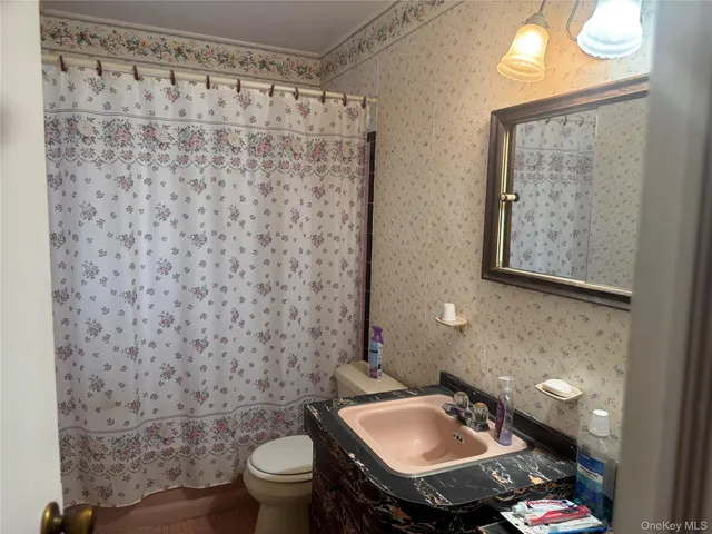 a bathroom with a sink toilet and a mirror