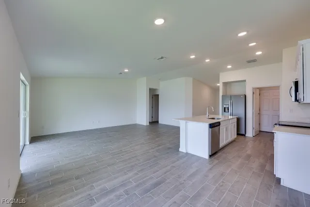 a view of kitchen with kitchen island wooden floor appliances and center island