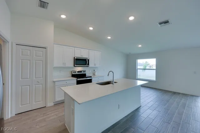 a kitchen with a sink a microwave a refrigerator and cabinets