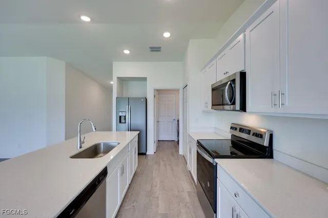 a kitchen with granite countertop a sink dishwasher stove and microwave with wooden floor