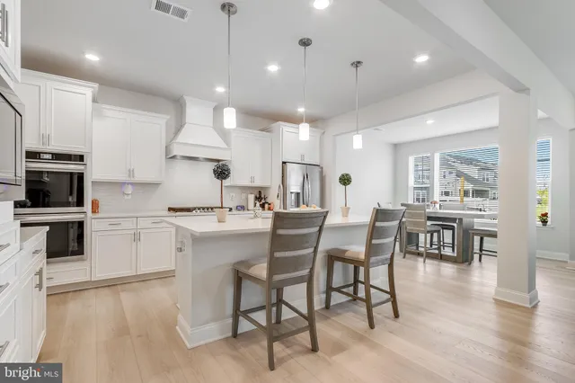 a kitchen with stainless steel appliances granite countertop a stove top oven a sink dishwasher a dining table and chairs with wooden floor