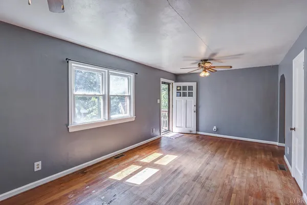 an empty room with wooden floor and windows