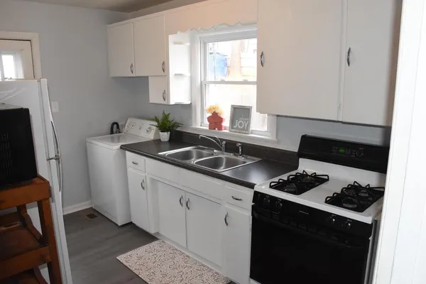 a kitchen with sink a stove and white cabinets