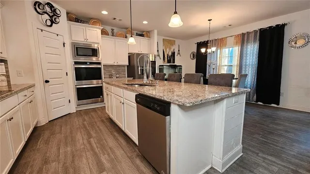 a kitchen with stainless steel appliances kitchen island granite countertop a table and chairs