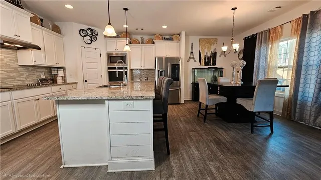 a kitchen with a refrigerator a sink dishwasher a dining table and chairs with wooden floor