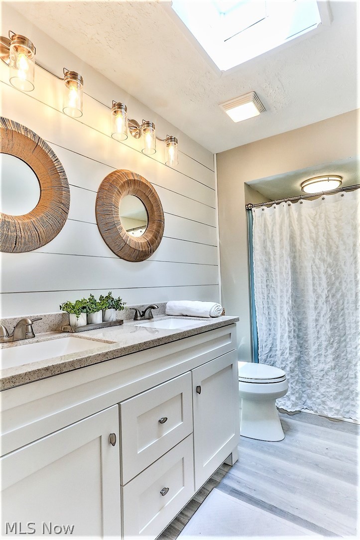 2116 Portage Line Road Mogadore, OH 44260 - Photo 22 of 35 *BEAUTIFUL MASTER BATHROOM WITH NEW LUXURY FLOORING, SHIPLAPPED WALL, WHITE VANITY WITH GRANITE COUNTERTOPS AND HIS AND HER SINKS WITH HIS AND HER MIRRORS AND SCONCE LIGHTING! ALSO A SKYLIGHT ~