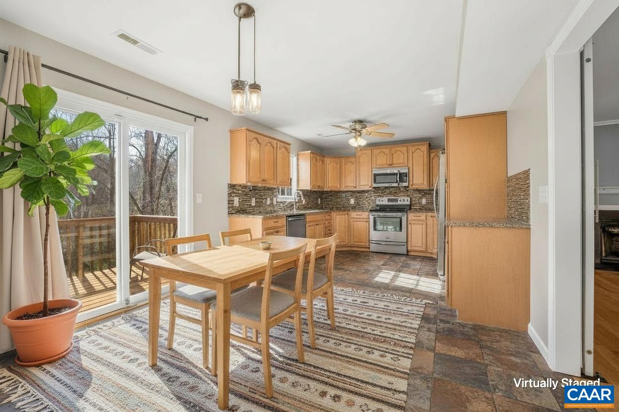 462 Fox Hunters Lane Madison, VA 22727 - Photo 18 of 65 a kitchen with stainless steel appliances granite countertop a stove a refrigerator a microwave oven with a dining table and chairs with wooden floor