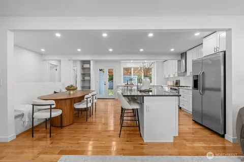 a kitchen with stainless steel appliances granite countertop a table chairs sink refrigerator and microwave