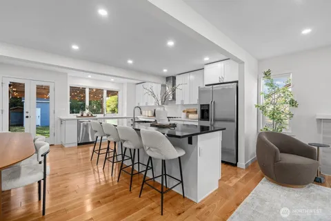 a kitchen with stainless steel appliances granite countertop a refrigerator a stove a dining table and chairs with wooden floor