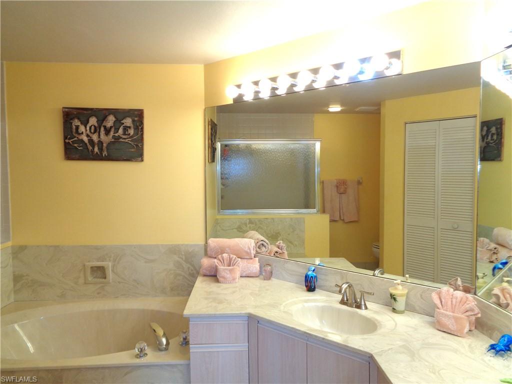 6260 Bellerive Avenue, Unit 4 Naples, FL 34119 - Photo 25 of 36 a bathroom with a tub a sink and a mirror