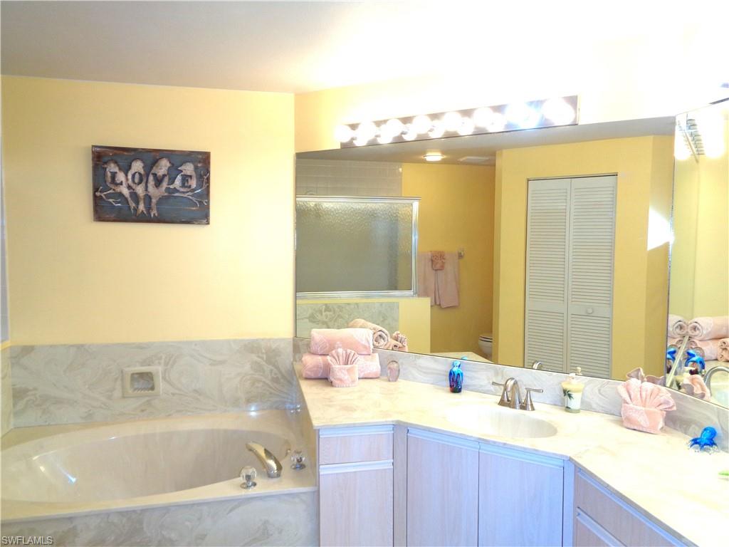 6260 Bellerive Avenue, Unit 4 Naples, FL 34119 - Photo 26 of 36 a bathroom with a bathtub sink and mirror