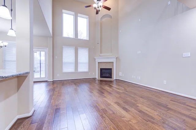 a view of an empty room with a fireplace and wooden floor