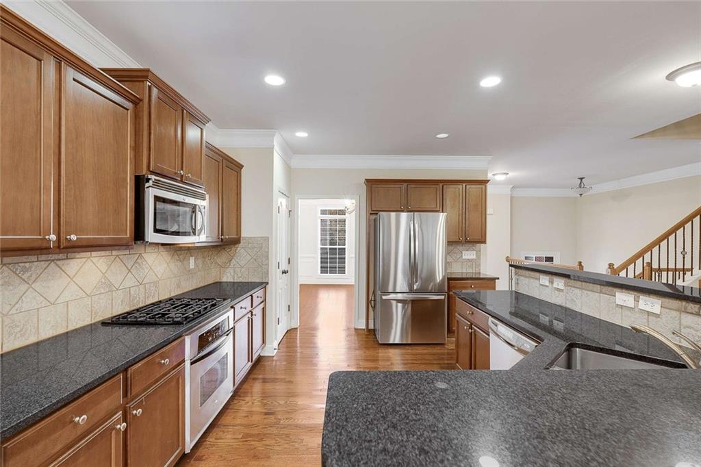 3199 Buck Way Alpharetta, GA 30004 - Photo 7 of 45 a kitchen with stainless steel appliances granite countertop a refrigerator a stove and a sink with wooden floor