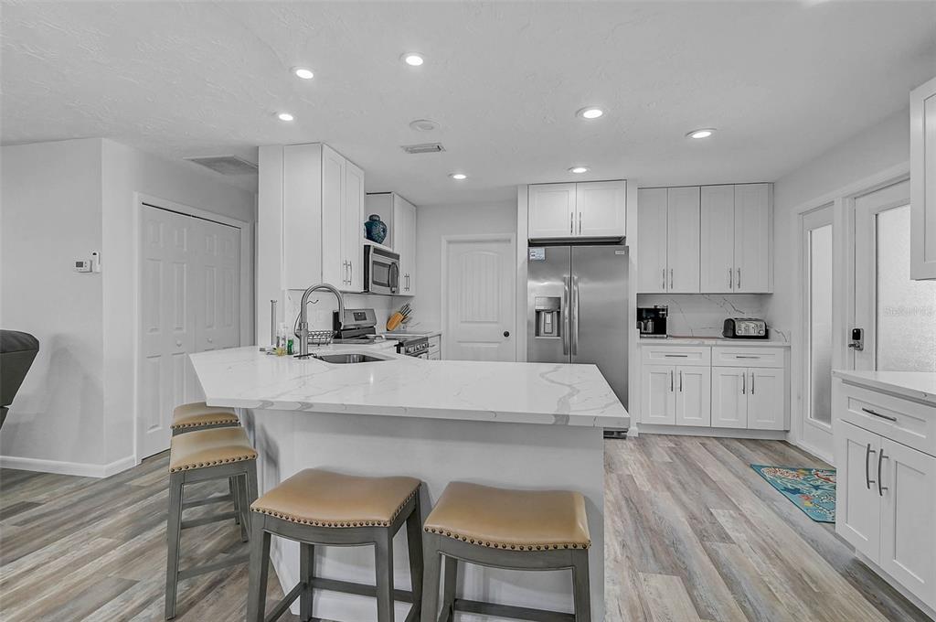6308 Midnight Pass Road, Unit 6 Sarasota, FL 34242 - Photo 6 of 44 a kitchen with kitchen island a stove a table and chairs in it