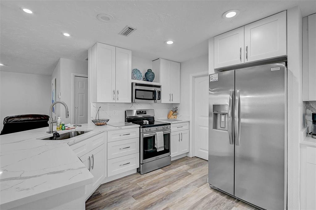 6308 Midnight Pass Road, Unit 6 Sarasota, FL 34242 - Photo 7 of 44 a kitchen with white cabinets and stainless steel appliances