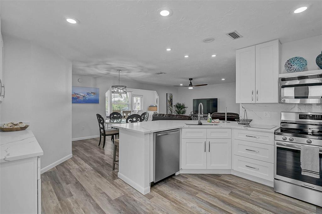 6308 Midnight Pass Road, Unit 6 Sarasota, FL 34242 - Photo 8 of 44 a kitchen with stainless steel appliances granite countertop a stove top oven a sink dishwasher and a dining table with wooden floor