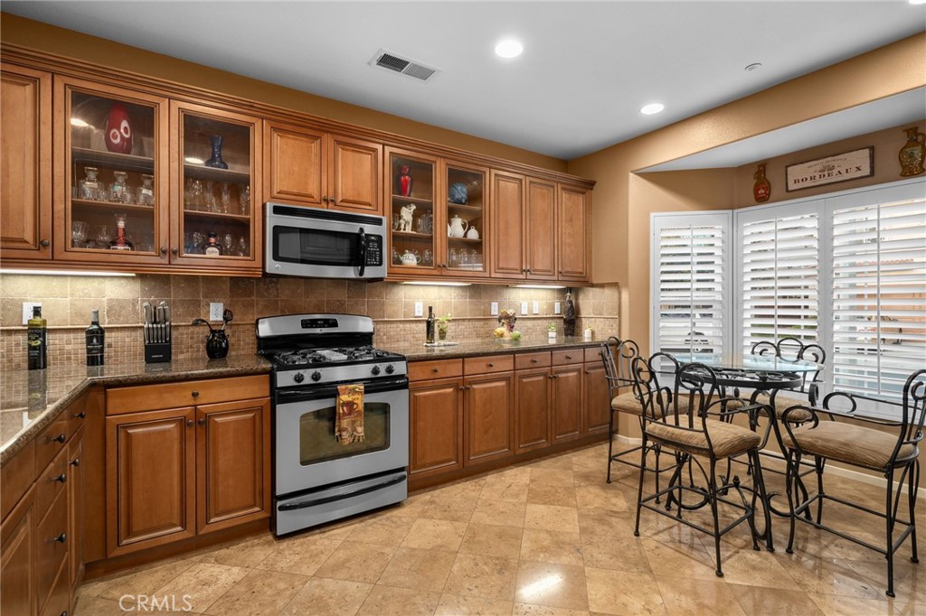 4140 Garvey Way Riverside, CA 92501 - Photo 6 of 25 a kitchen with stainless steel appliances granite countertop a stove top oven a sink a dining table and chairs
