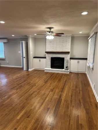 a view of a livingroom with a fireplace a ceiling fan and wooden floor