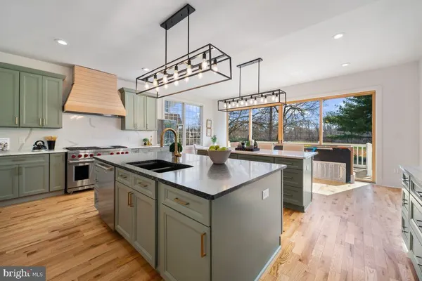 a kitchen with stainless steel appliances granite countertop a sink a stove and a wooden floors