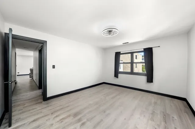 a view of an empty room with glass door and wooden floor