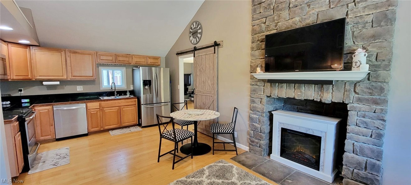 5770 Jaycox Road North Ridgeville, OH 44039 - Photo 5 of 31 Kitchen featuring a fireplace, light hardwood flooring, lofted ceiling, brown cabinets, and appliances with stainless steel finishes