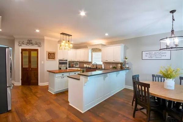a kitchen with stainless steel appliances granite countertop a sink a stove a dining table and chairs