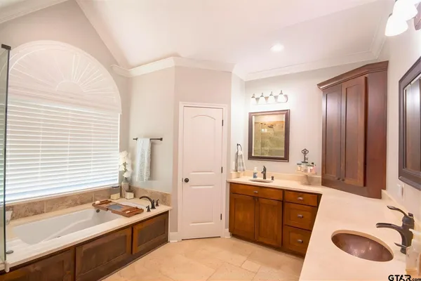 a bathroom with a sink double vanity granite tub shower and mirror