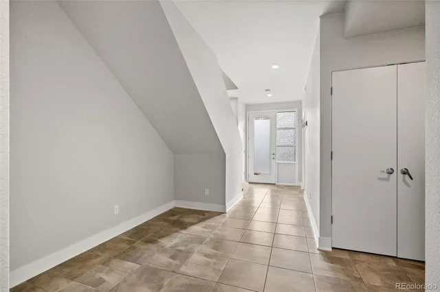 a view of a hallway to an empty room with wooden floor