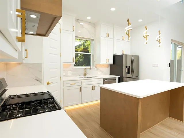 a kitchen with a sink a stove a refrigerator and white cabinets