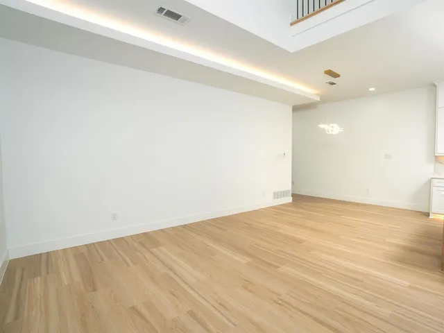 a view of kitchen with stainless steel appliances kitchen island empty cabinets and wooden floor