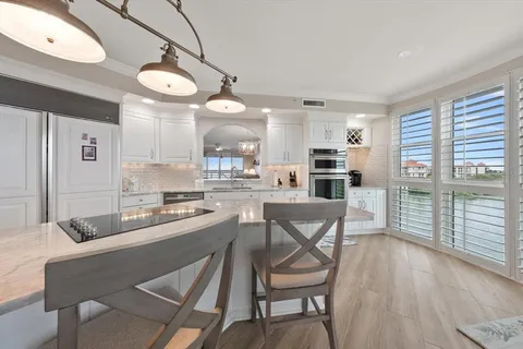 a kitchen with stainless steel appliances granite countertop a dining table chairs and granite counter tops