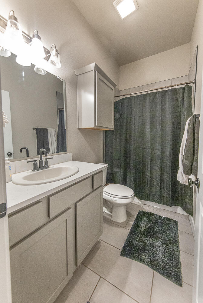 7334 29th Street Lubbock, TX 79407 - Photo 18 of 31 a bathroom with a sink a toilet a mirror and shower