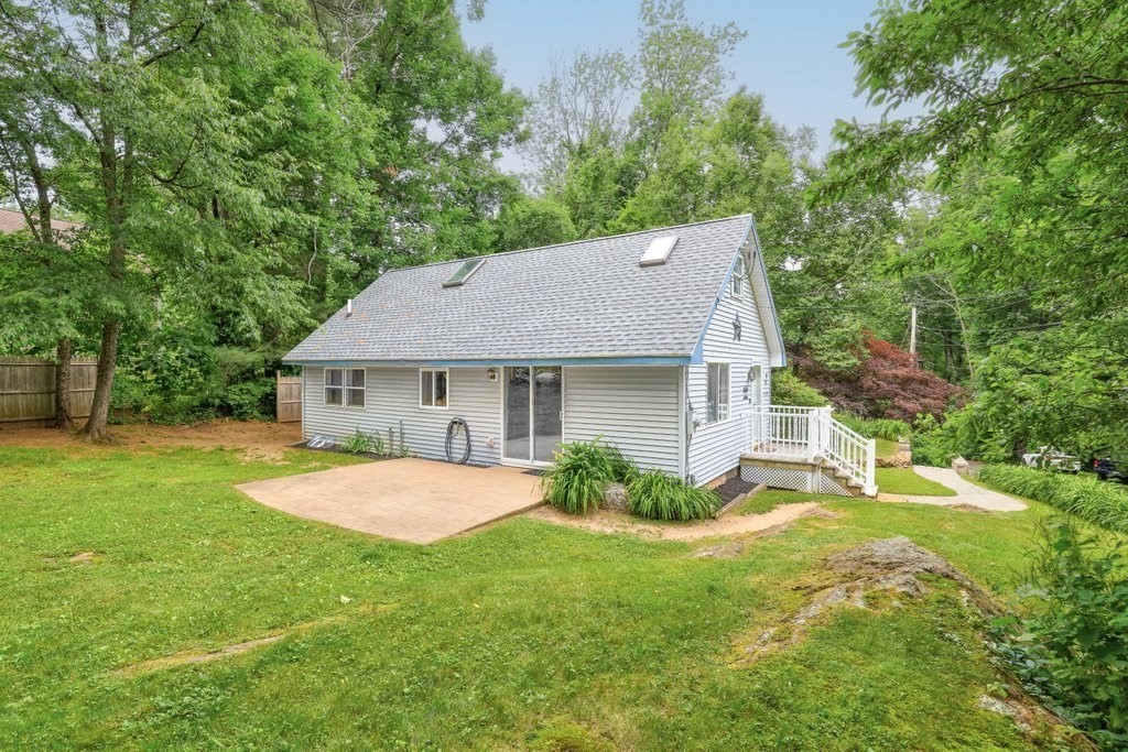a view of a house with a yard and a large tree