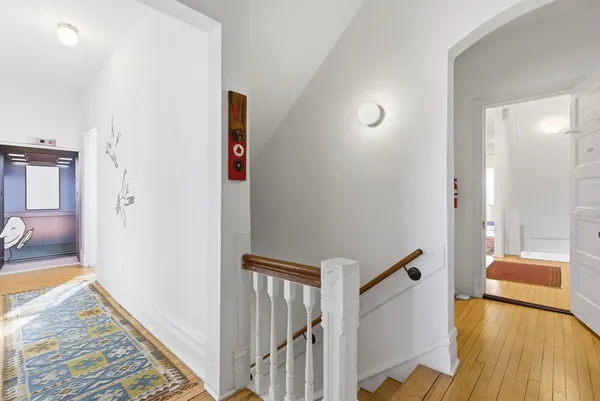 a view of a hallway to a livingroom with wooden floor and furniture