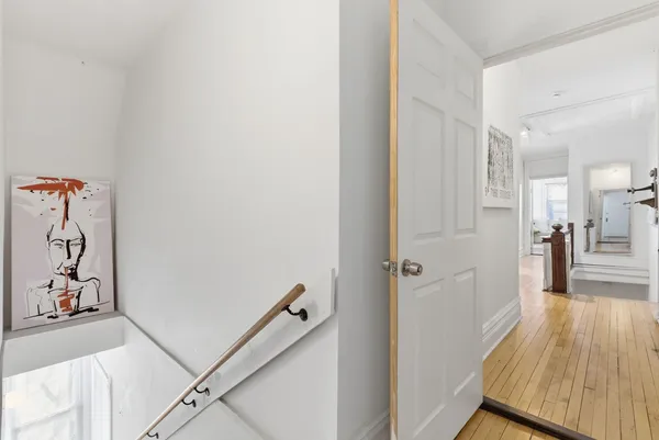 a view of a hallway with wooden floor and living room