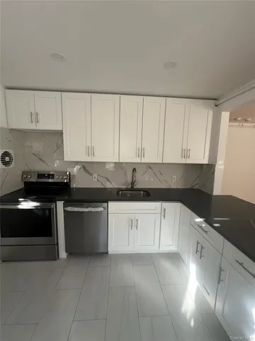 a kitchen with granite countertop a sink a stove and cabinets