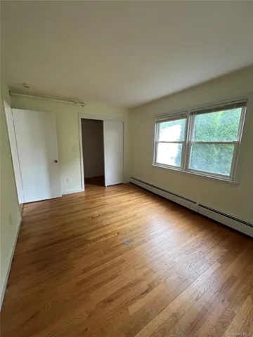 a view of an empty room with wooden floor and windows