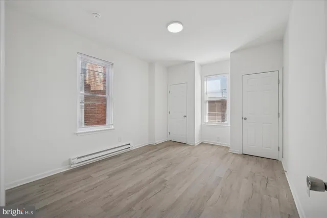 an empty room with wooden floor and windows