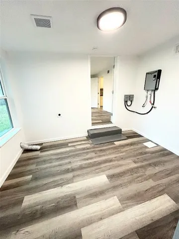 a view of an empty room with wooden floor and a window